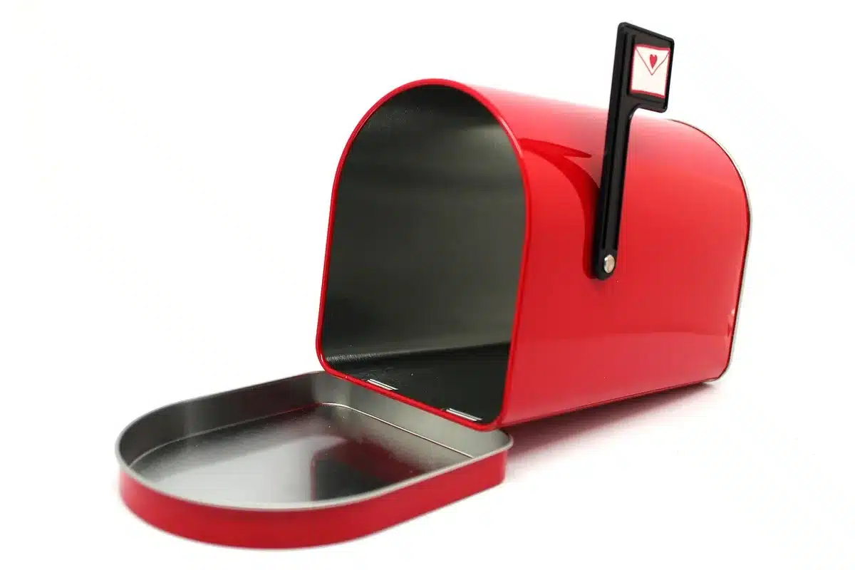 Boîte aux lettres d'immeuble avec une quittance partiellement visible et une main anonyme
