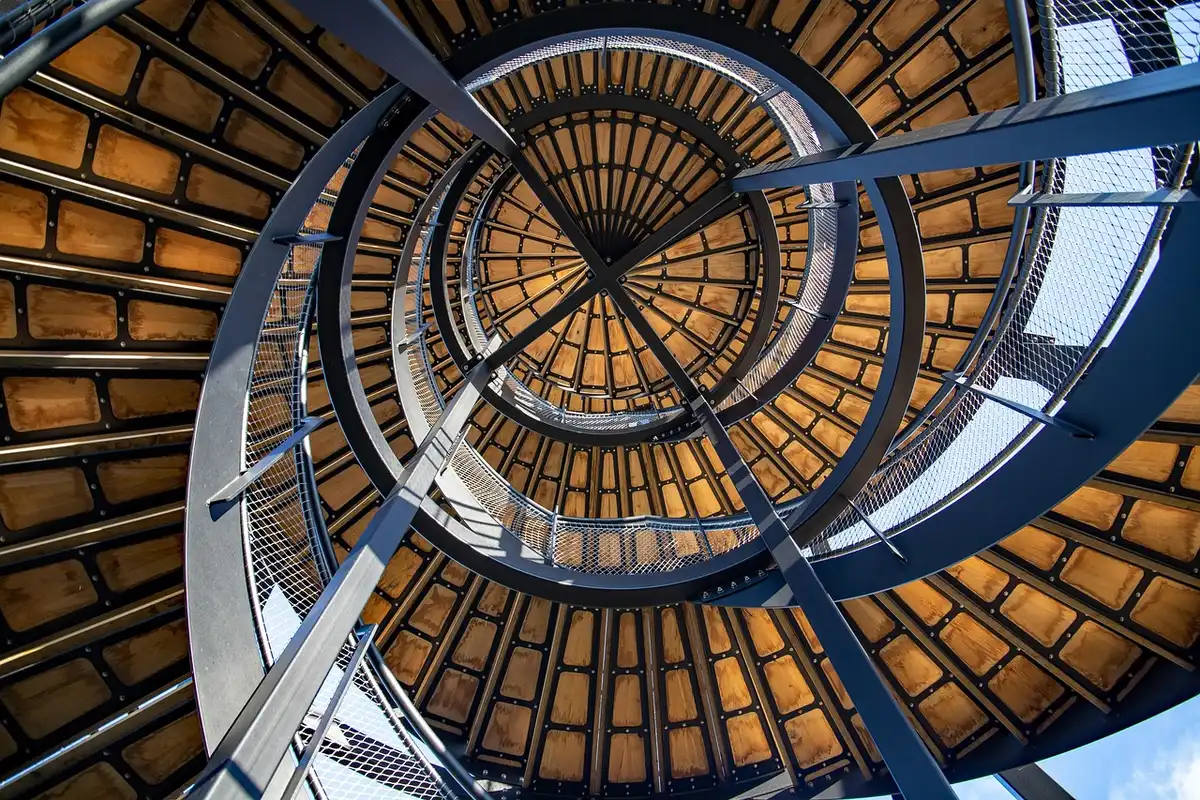 Escalier colimaçon en spirale en bois et métal dans un intérieur avec mezzanine