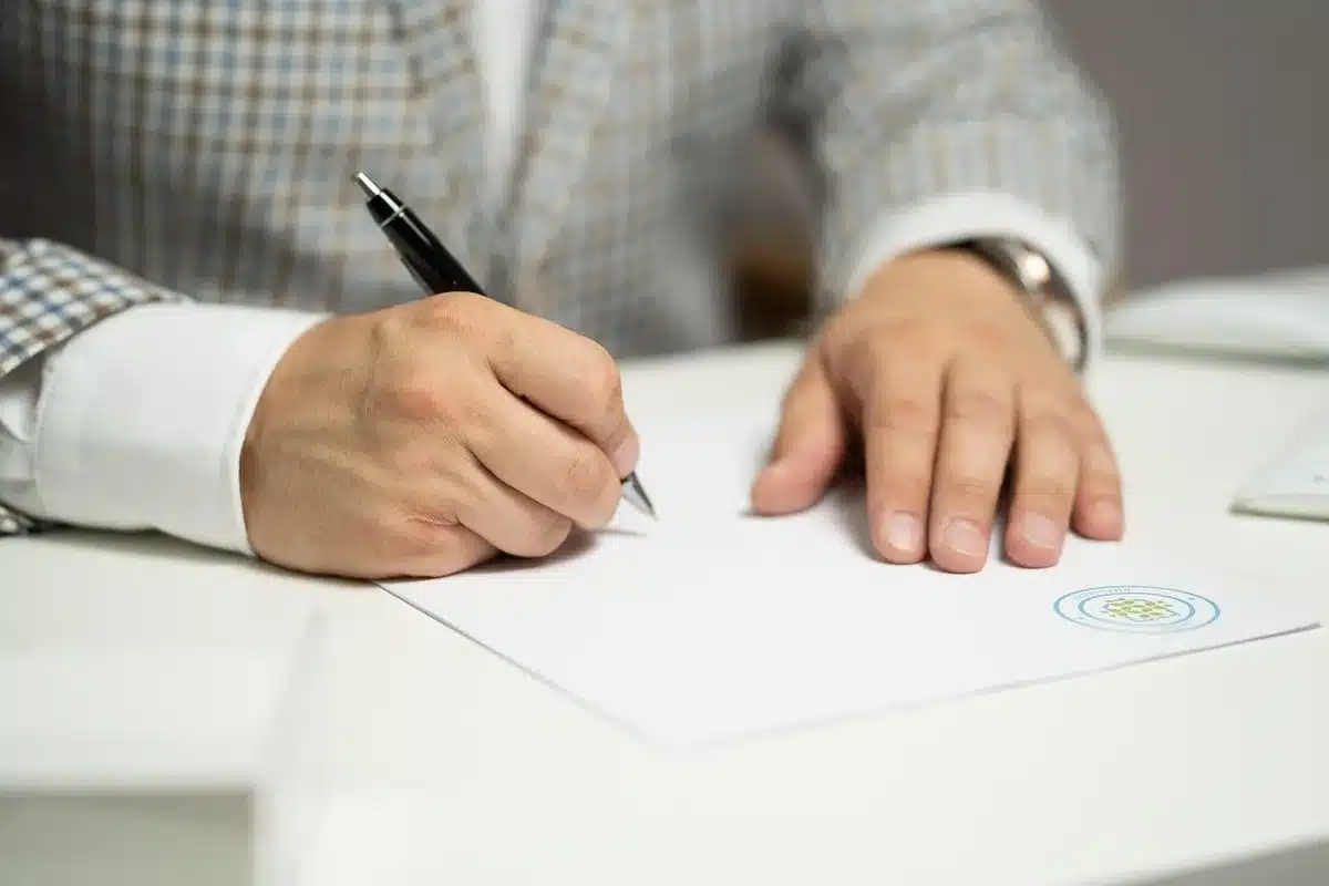 Deux mains tenant une notice d'information et un devis posés sur une table en journée