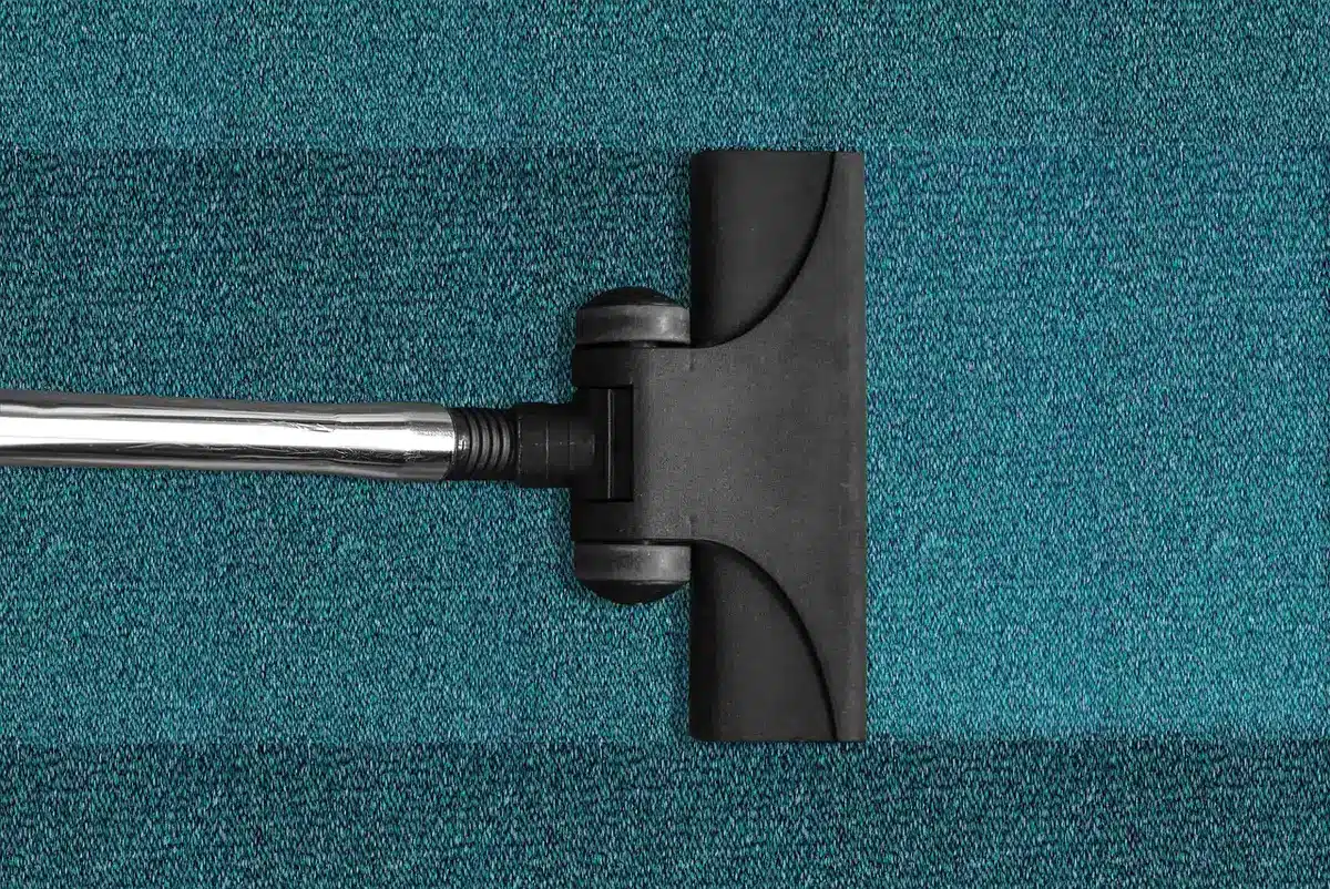 Aspirateur avec embout brosse passant sur un canapé