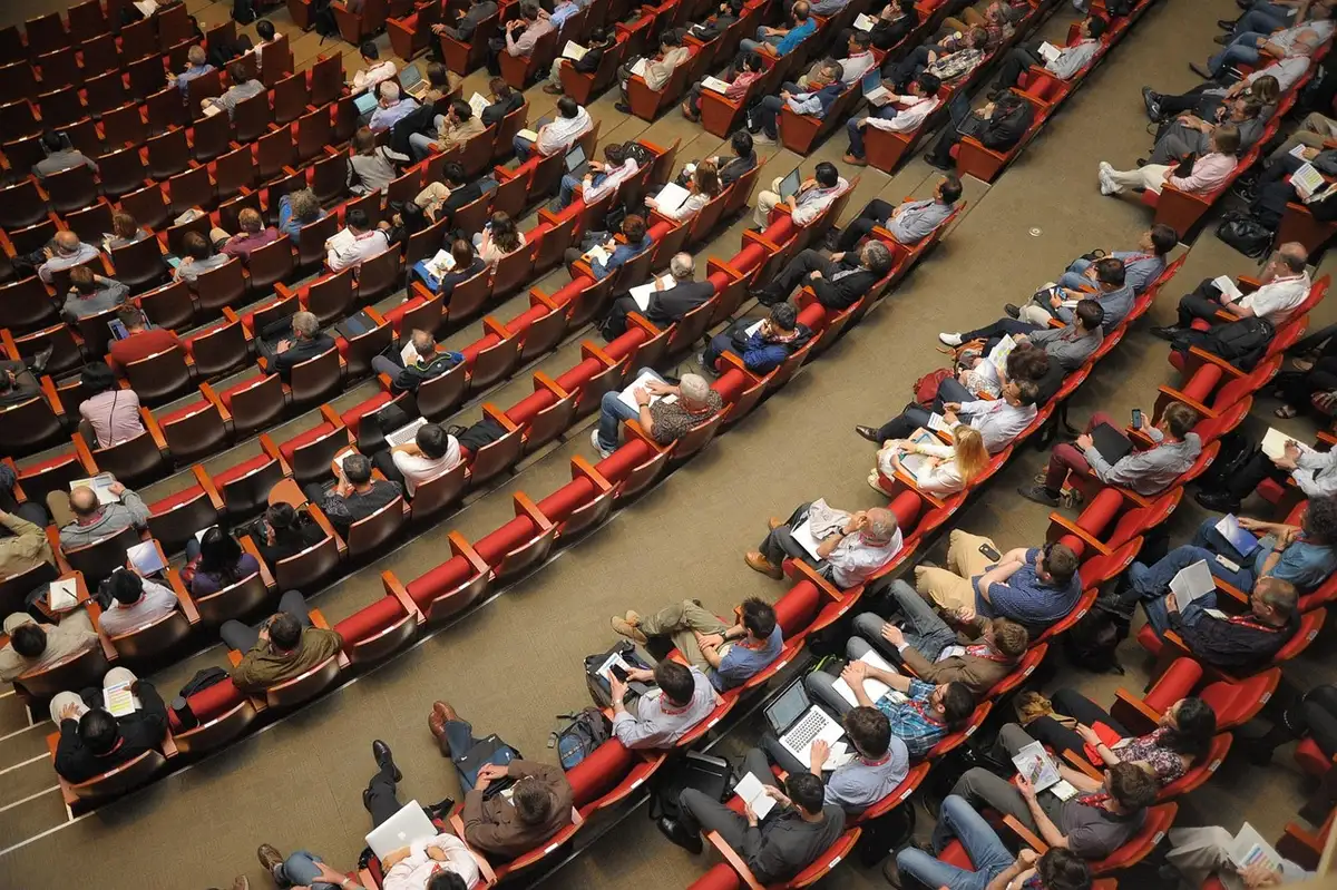 Espace d'accueil du village du Congrès avec stands et chaises, lumière du jour