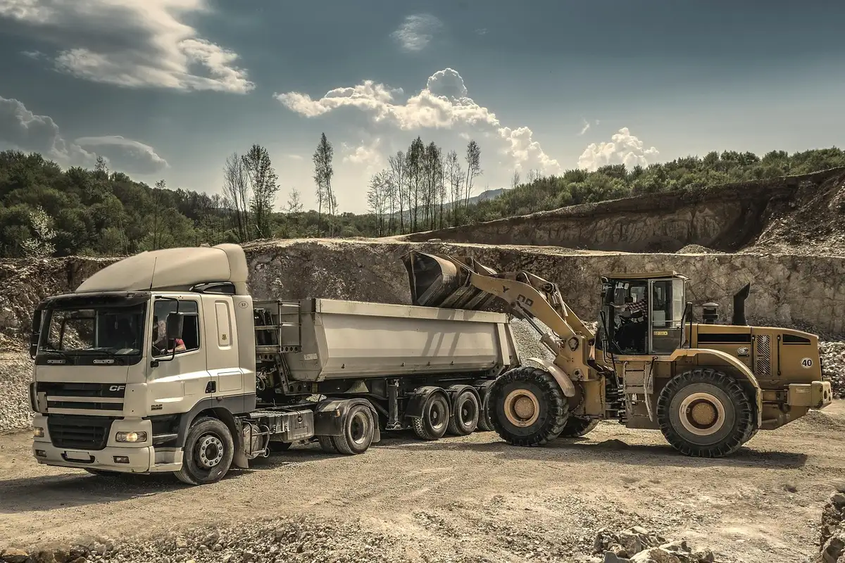 Plateforme de chantier côtier avec engins de terrassement et pylônes électriques en arrière-plan