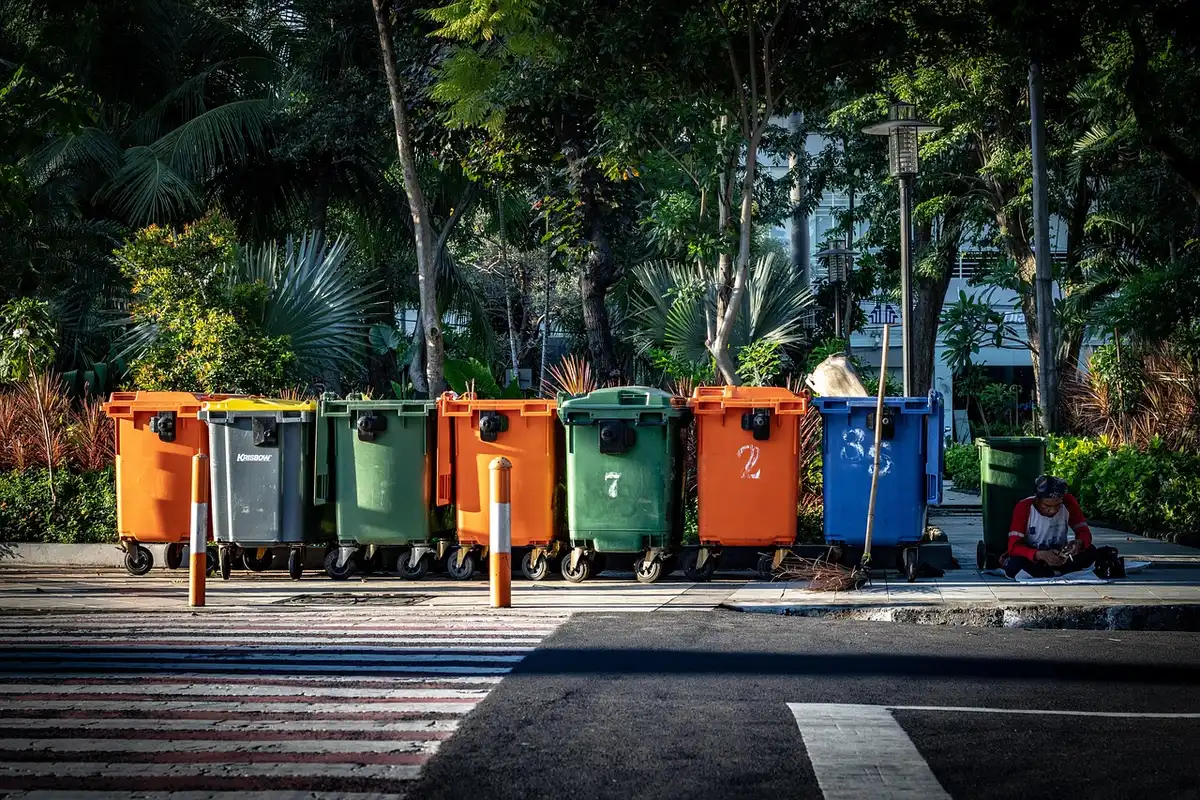 Mains anonymes triant des emballages près d'un bac de recyclage