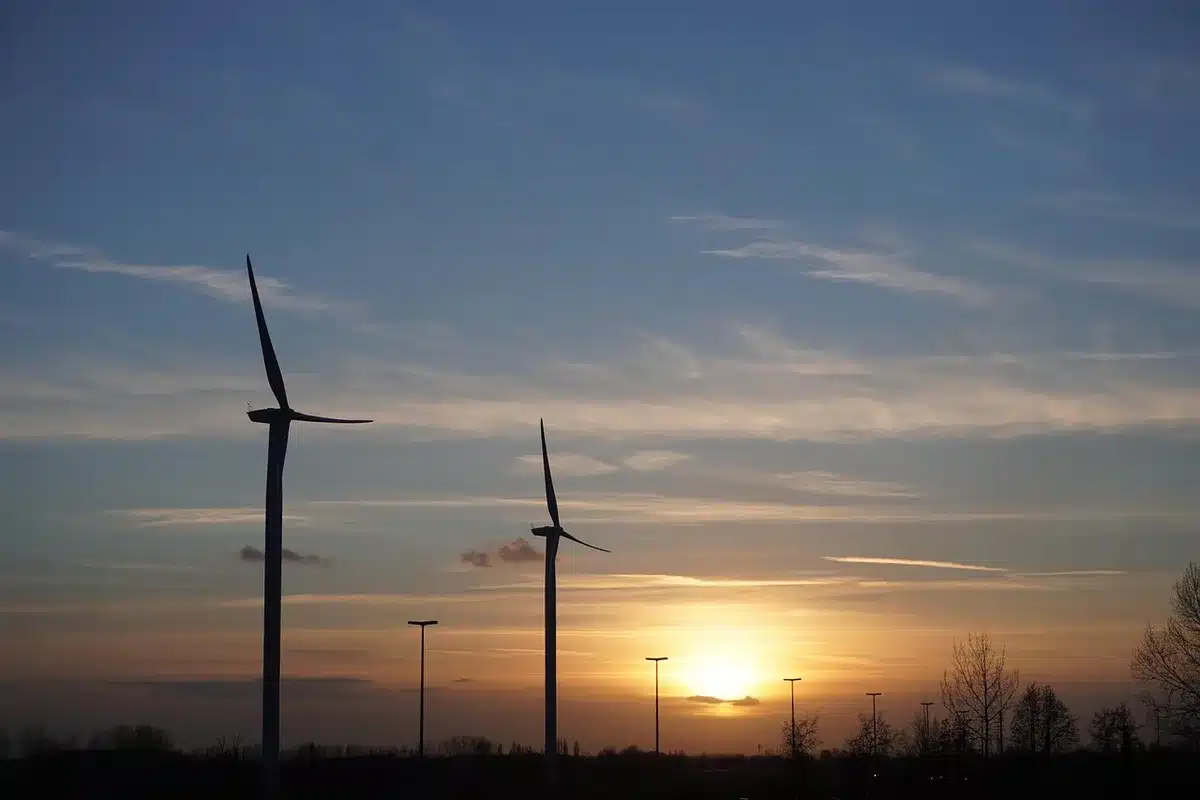 Toit solaire industriel et éolienne au coucher avec silhouettes d'ouvriers floues
