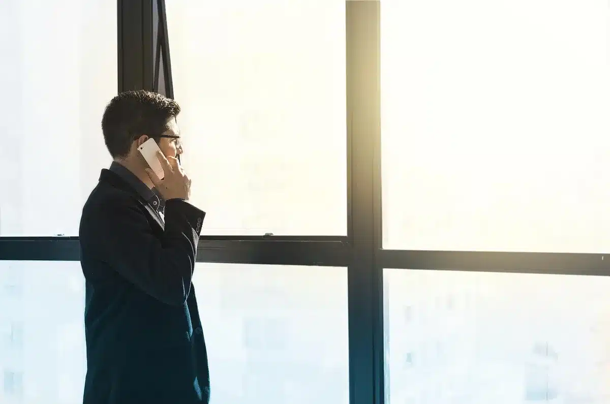 Jeune regardant des intérieurs sur un téléphone, évoquant la comparaison sociale