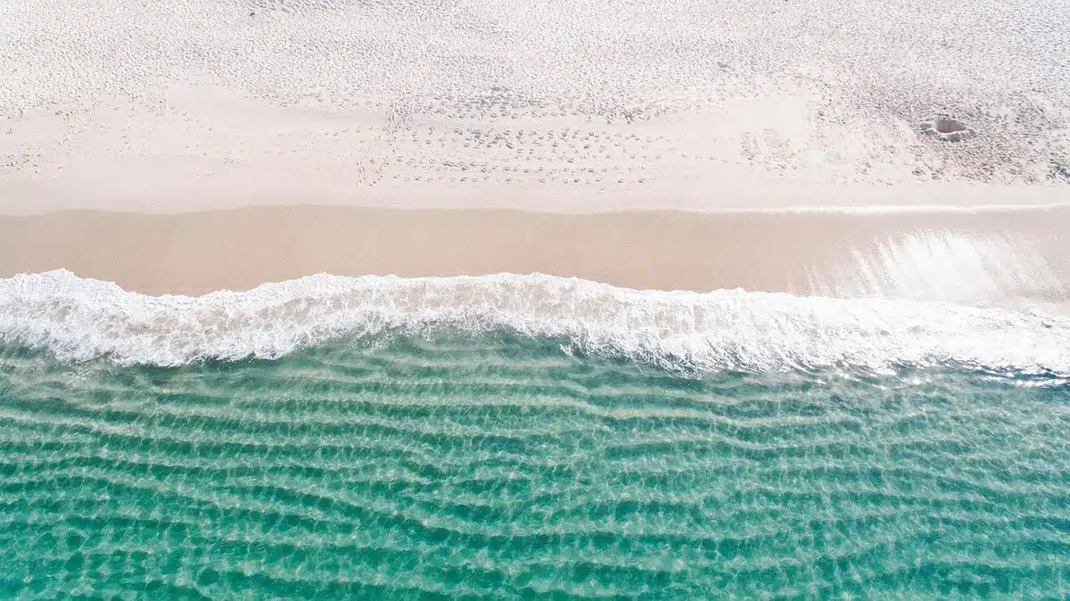 Plage urbaine sable, tour de surveillance et plan d'eau en arrière‑plan, sans personnes identifiables