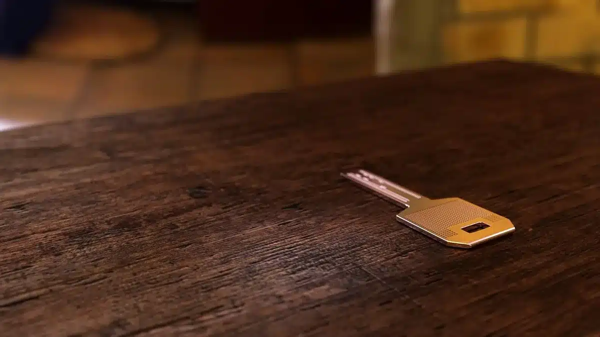Main anonyme tenant des clefs au-dessus de plans et d'une calculatrice sur un bureau