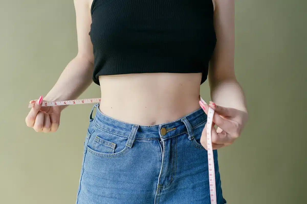 Personne prenant des mesures dans une pièce vide avec un mètre ruban