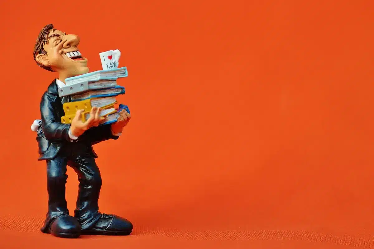 Paperasse fiscale, calculatrice et lunettes sur un bureau éclairé par la fenêtre