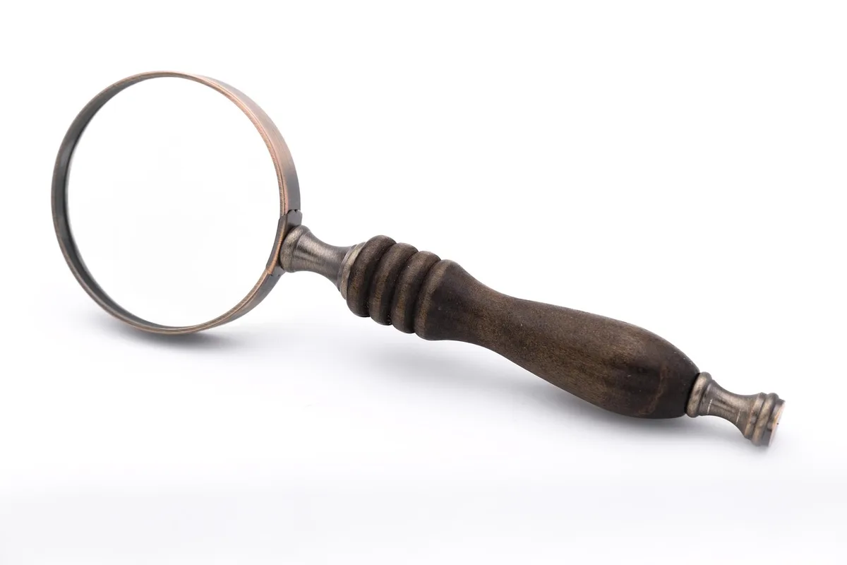 Détail d'un meuble laqué ancien examiné à la loupe dans une boutique baignée de lumière