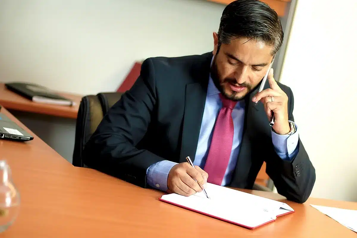 Deux mains tenant un document de cautionnement devant une table avec contrats