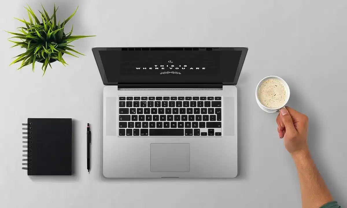 Bureau en journée avec documents techniques et ordinateur portable, mains anonymes manipulant des papiers