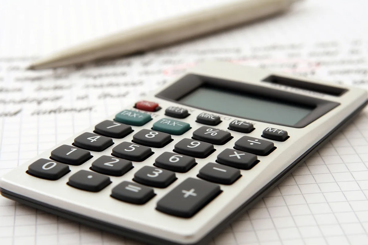 Calculatrice, documents et loyer estimé sur une table pour calculer le rendement