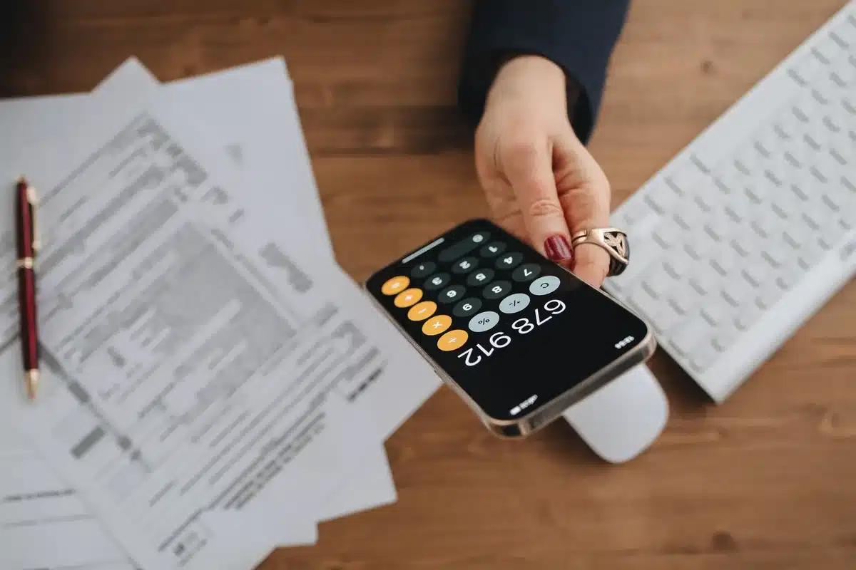 Bureau domestique en journée avec documents fiscaux et calculatrice sur une table en bois