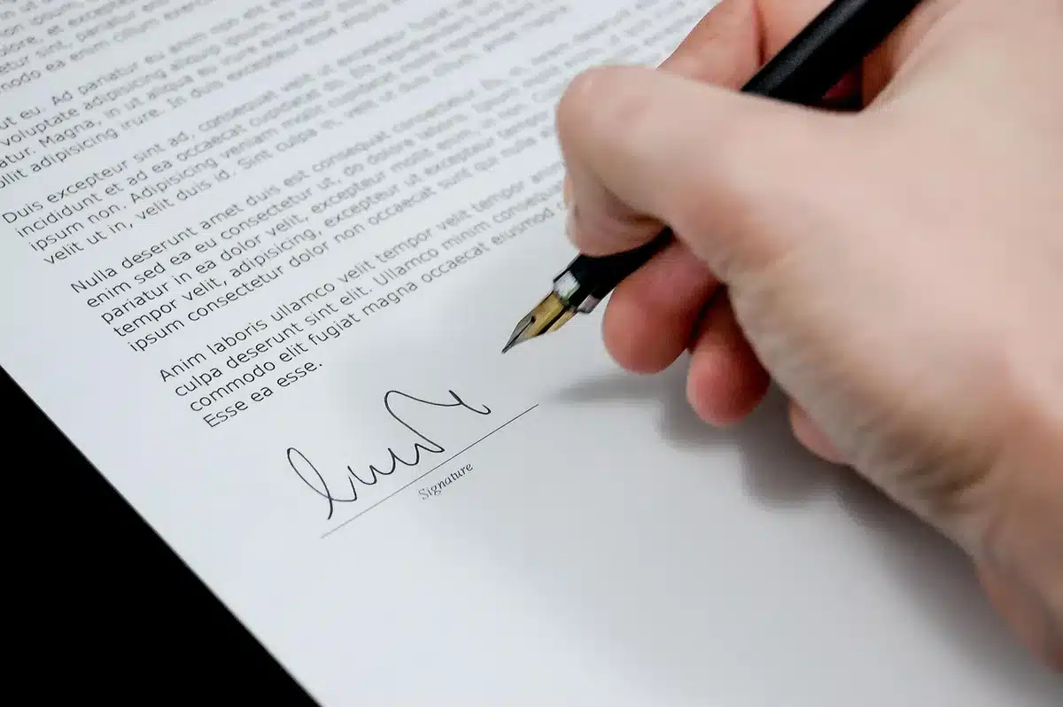 Mains tenant un contrat signé posé près d'une calculatrice