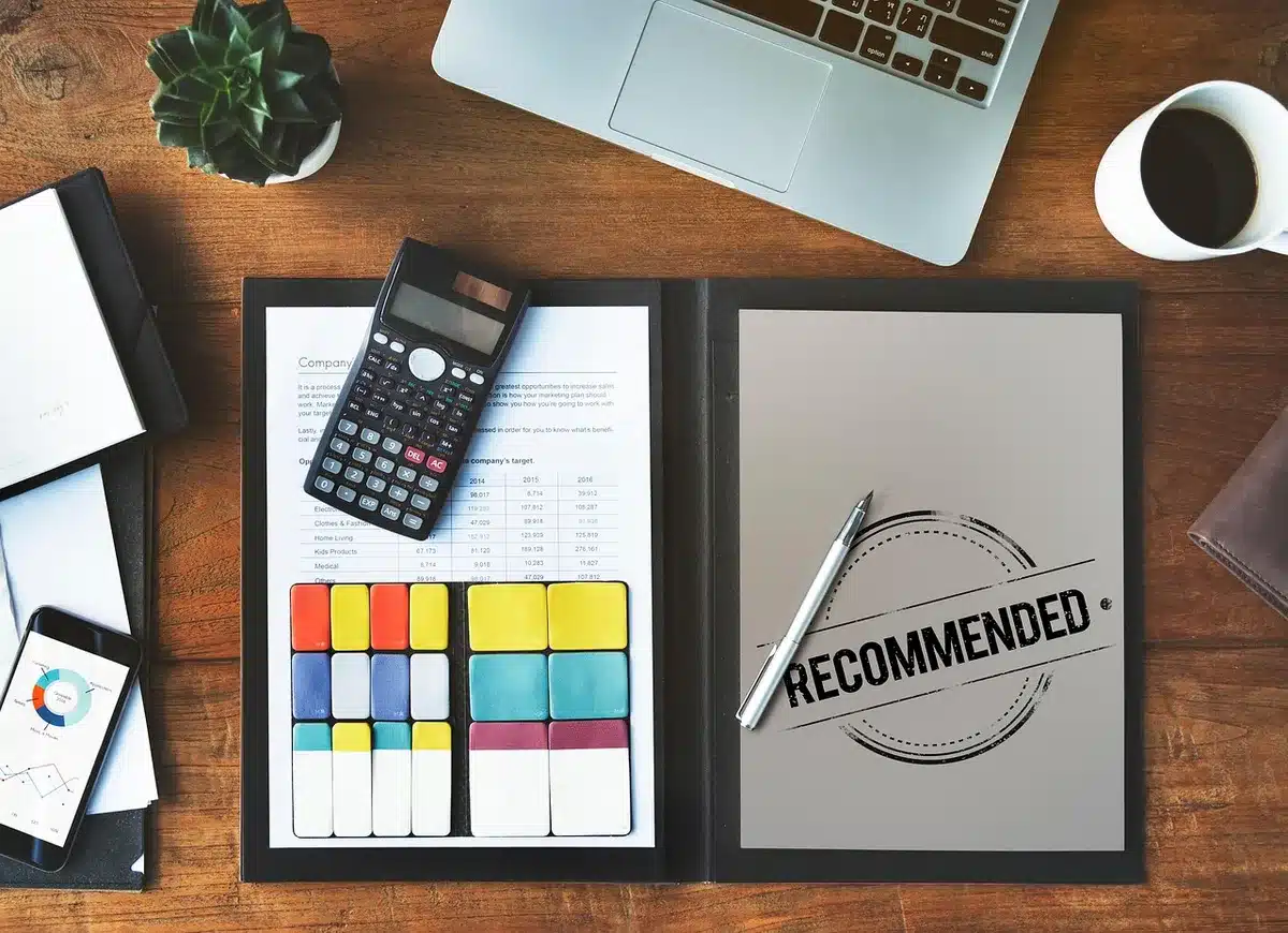 Bureau en journée avec contrat d'assurance, calculatrice et mains sur une table