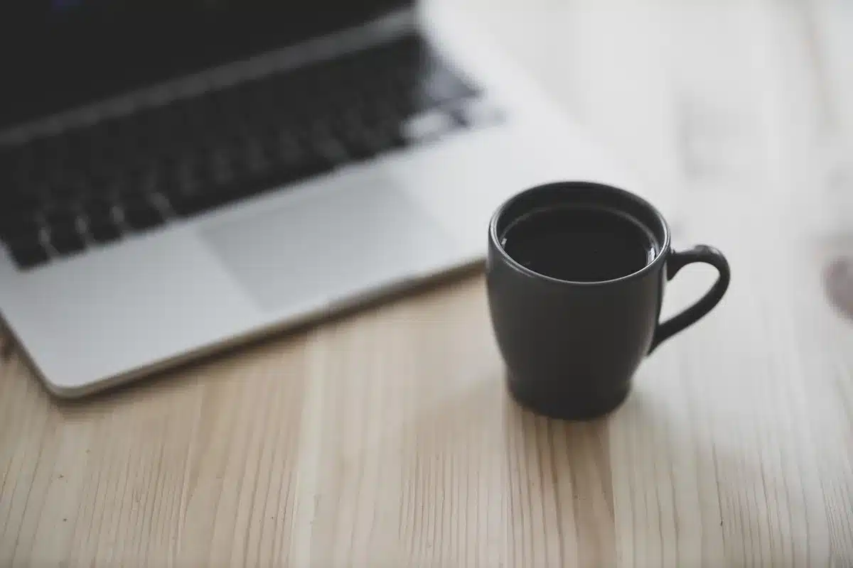 Bureau lumineux avec ordinateur affichant graphiques boursiers, carnet et tasse de café