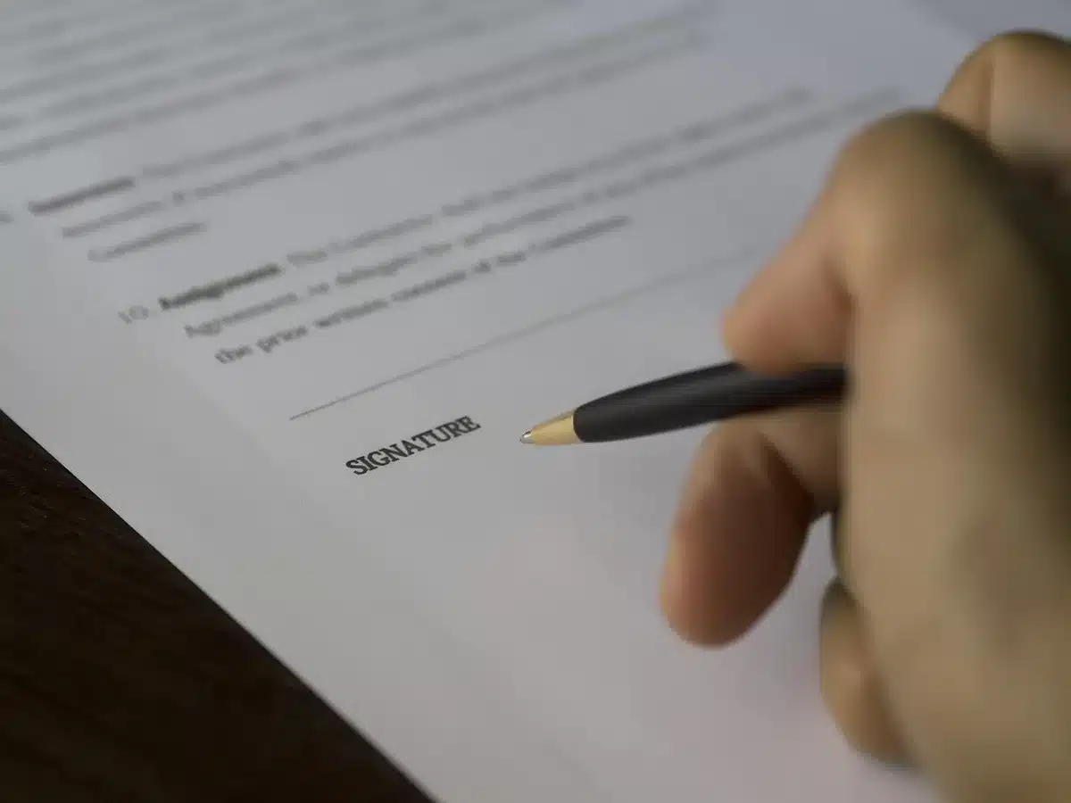 Main signant un contrat de location sur une table ensoleillée