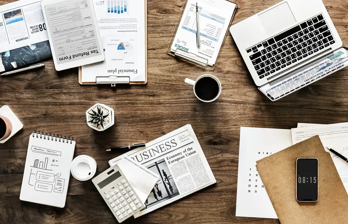 Bureau lumineux avec papiers, calculatrice et mains prenant des notes