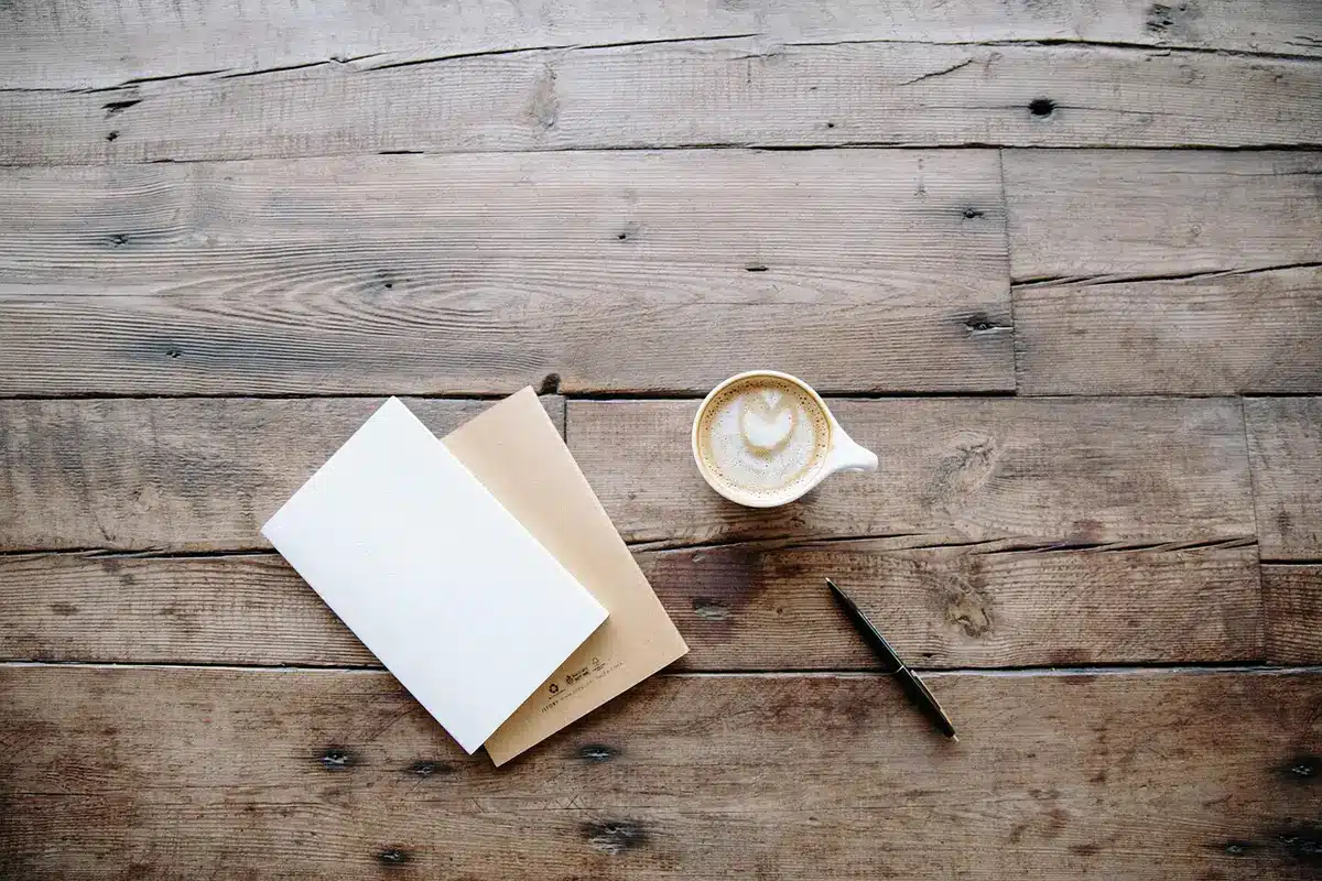 Carnet ouvert, stylo et tasse sur une table de cuisine en plein jour
